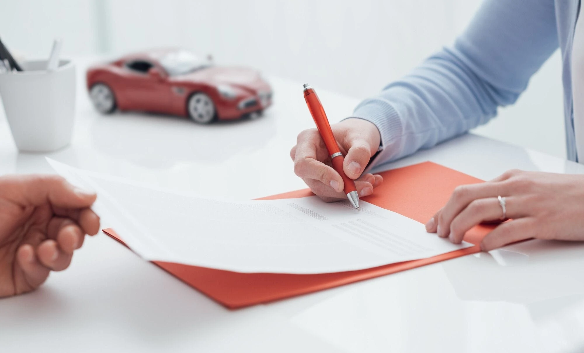A person signs a contract with a red pen A person signs a contract with a red pen